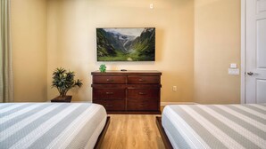 Een hotelkamer met twee bedden, een dressoir, een schilderij van een berglandschap en een potplant.