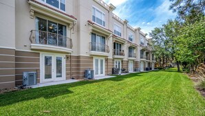 A row of townhouses with balconies, a well-maintained lawn, and a clear sky. - Th155 - 3BR House Near Disney, Sleeps 8 Guests (Orlando)
