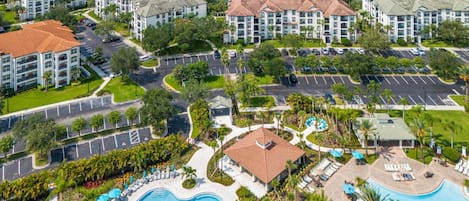 A resort with multiple buildings, a large swimming pool, and a lake in the background.