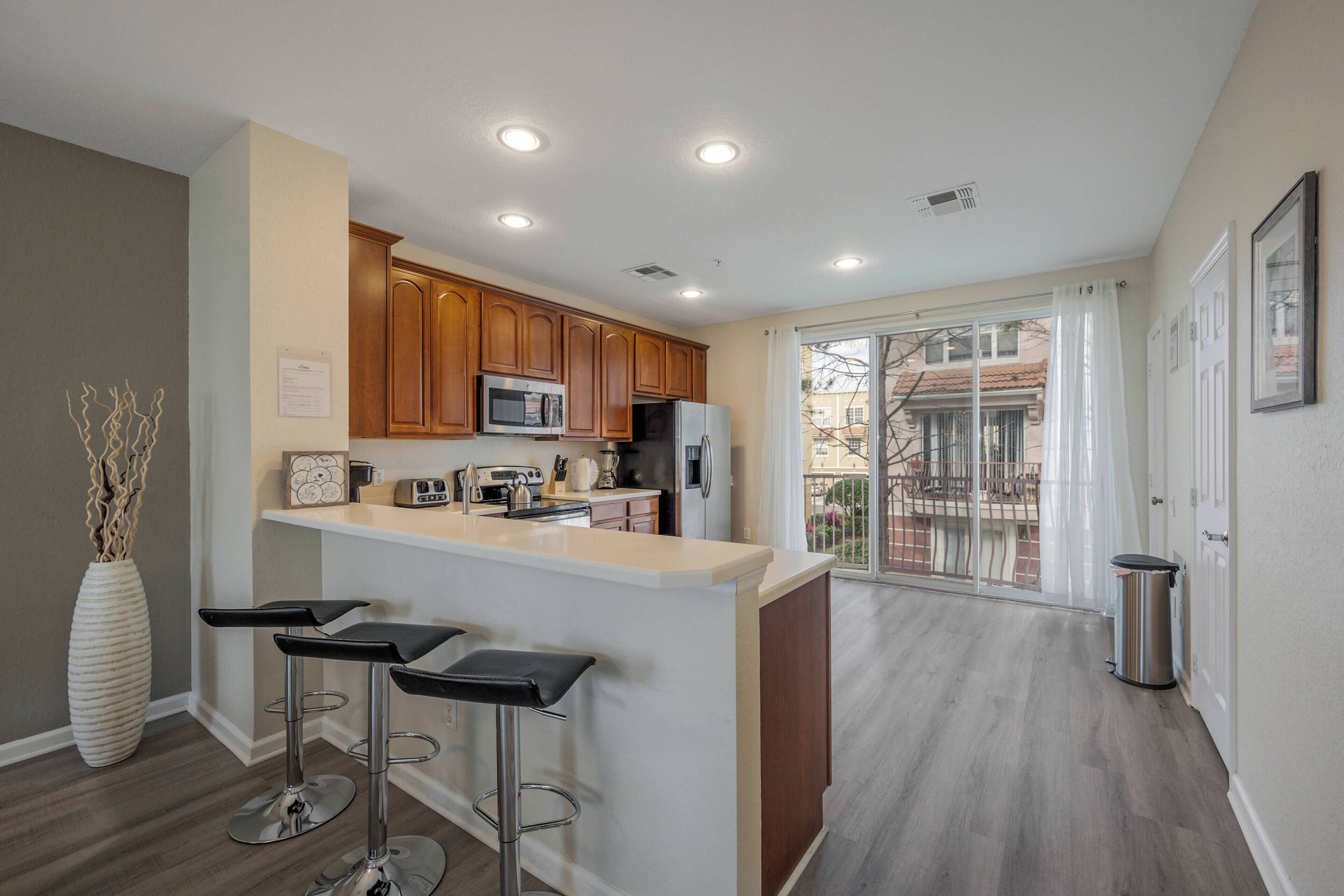 Una cocina moderna con armarios de madera, una isla central con taburetes y vistas al exterior.