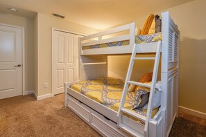 Ein Stockbett mit einer Leiter, einer Tür und einer gemusterten Bettdecke.