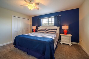 A bedroom with a bed, two bedside tables with lamps, a ceiling fan, a window with curtains, and a door. - Sl4802 - 4BR House With Pool Near Disney Area (Kissimmee)
