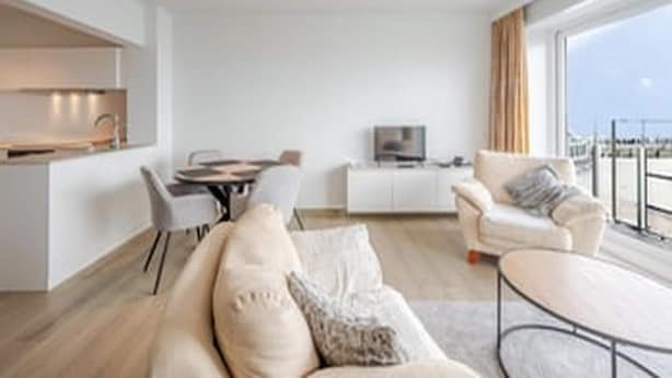 Een moderne woonkamer met een bank, een eettafel en een televisie.