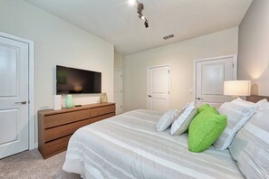 A bedroom with a bed, dresser, TV, and two doors. - Sl4926 - 4BR House With Pool Near Disney Area (Kissimmee)