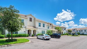A residential area with a row of townhouses, a parking lot, and a clear blue sky. - Sl3059 - 4BR House With Pool Near Disney (Kissimmee)