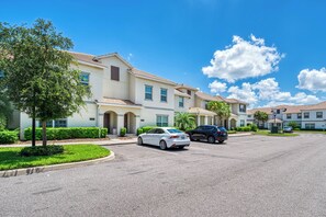 A residential area with a row of townhouses, a parking lot, and a clear blue sky. - Sl3059 - 4BR House With Pool Near Disney (Kissimmee)