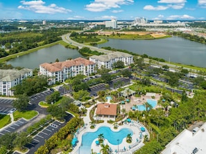 A resort with a swimming pool, parking, and a view of a lake. - Vcr2-409 Epic 3BR Condo Near Disney and Universal (Orlando)