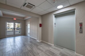 A hallway with a double door entrance, a fire alarm, and an elevator. - Vcr2-409 Epic 3BR Condo Near Disney and Universal (Orlando)