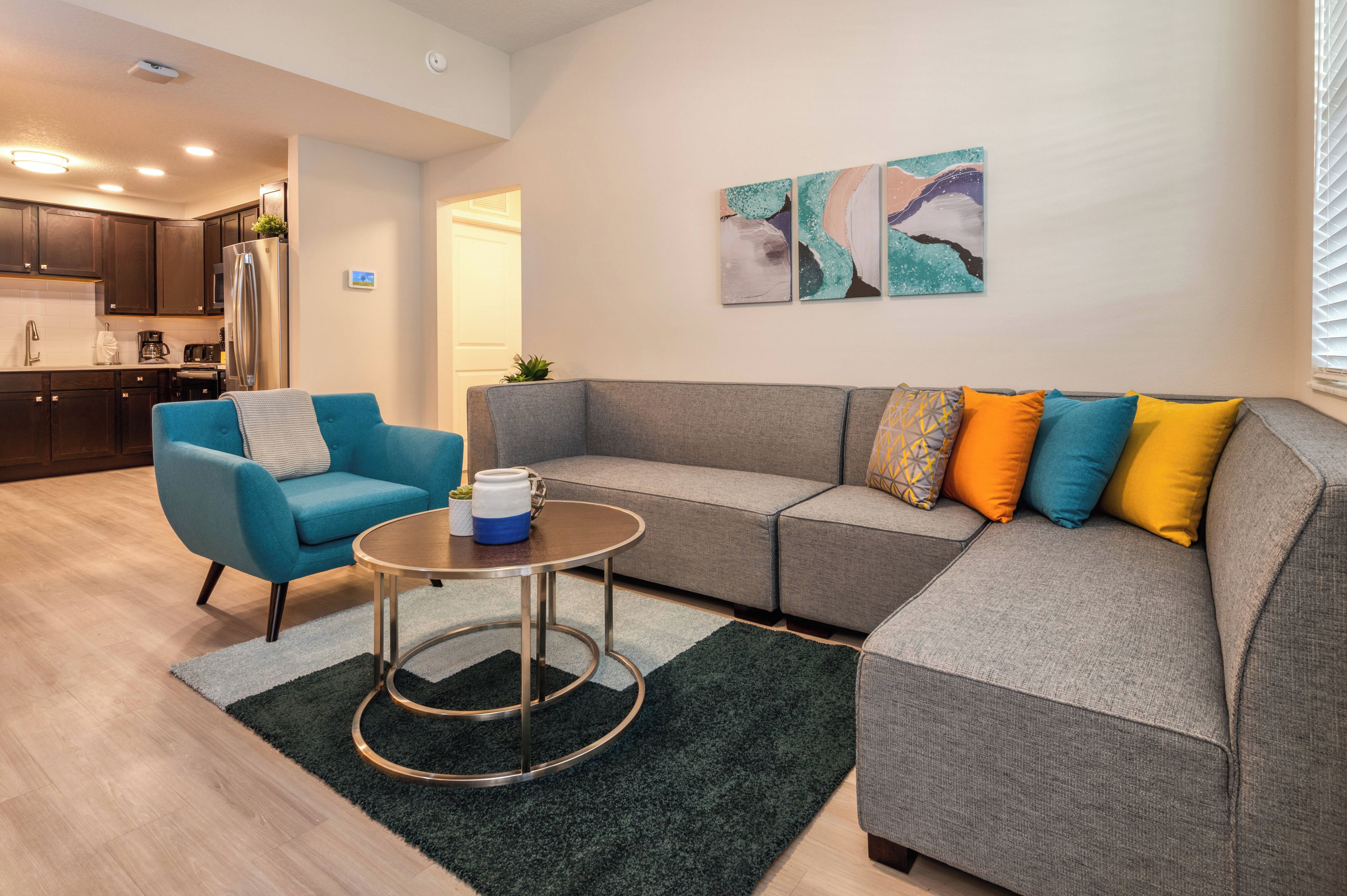 A modern living room with a grey sectional sofa, a blue armchair, and a small round coffee table.