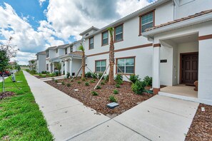 A row of townhouses with a front yard, a sidewalk, and a clear sky. - Sl4924 - 4BR House With Pool Near Disney (Kissimmee)