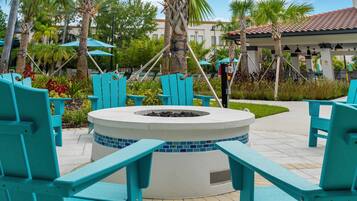 A circular outdoor seating area with turquoise chairs and a fire pit.