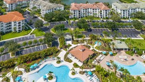 Een resort met meerdere gebouwen, een groot zwembad en een meer op de achtergrond.