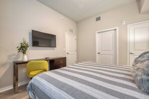 A bedroom with a bed, a desk with a chair, a TV, and two doors. - Vcr1-408 - 3BR Condo Near Disney and Universal (Orlando)