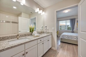 A modern bathroom with a granite countertop sink, a large mirror, and a hairdryer. - Vcr1-305- 3BR Condo Near Disney With Resort Access (Orlando)