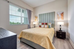 Quarto de hotel moderno com uma cama grande, duas mesas de cabeceira e uma escrivaninha.