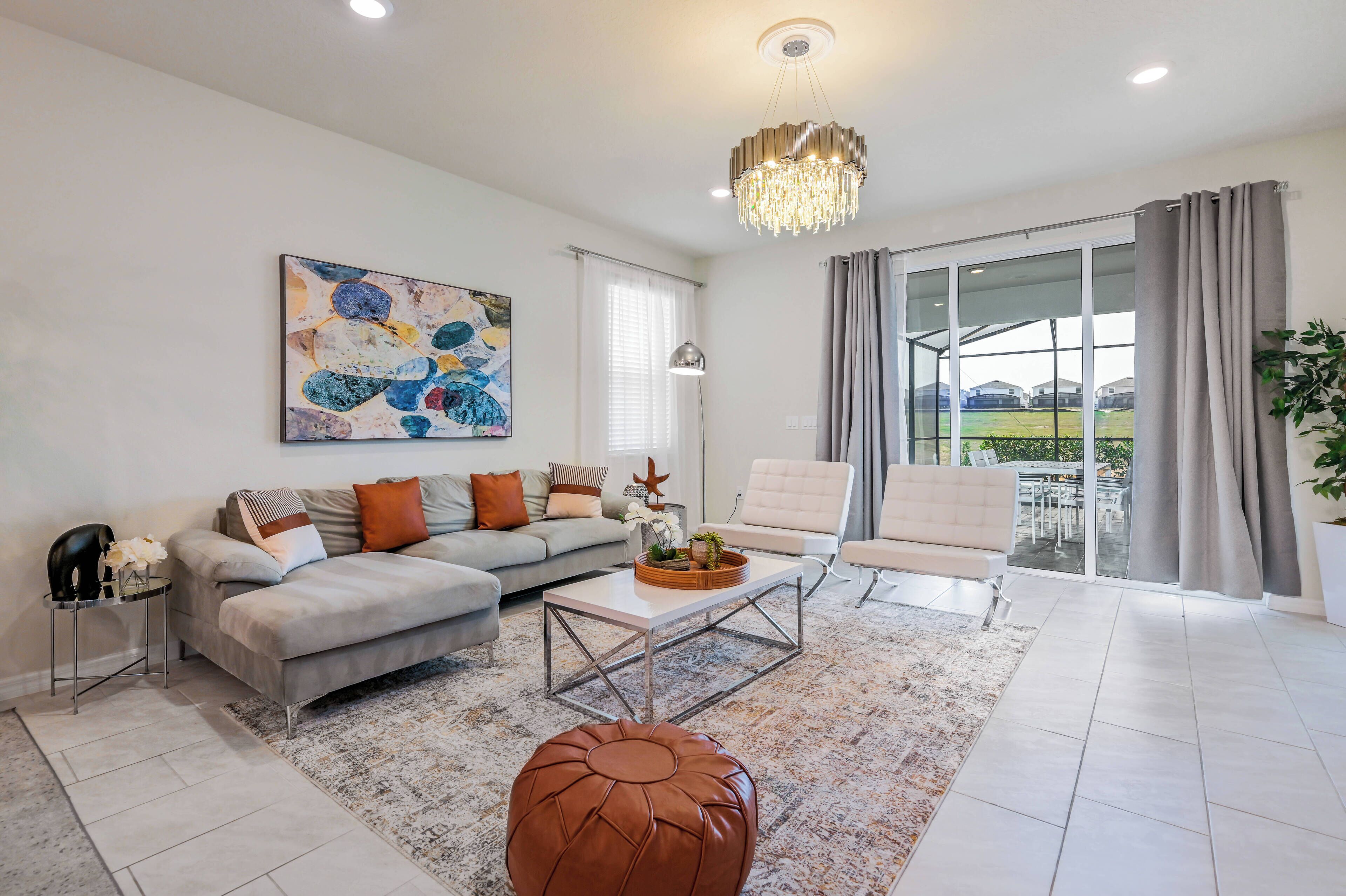 A modern living room with a sectional sofa, a coffee table, and a large window with a view of a green landscape.