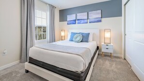 A neatly arranged bedroom with a large bed, bedside tables, and a view of the outdoors through the window. - Wi1196 - 7BR House With Pool Near Disney (Davenport)