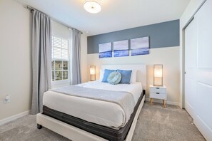 Ein ordentlich eingerichtetes Schlafzimmer mit einem großen Bett, Nachttischen und Blick ins Freie durch das Fenster.