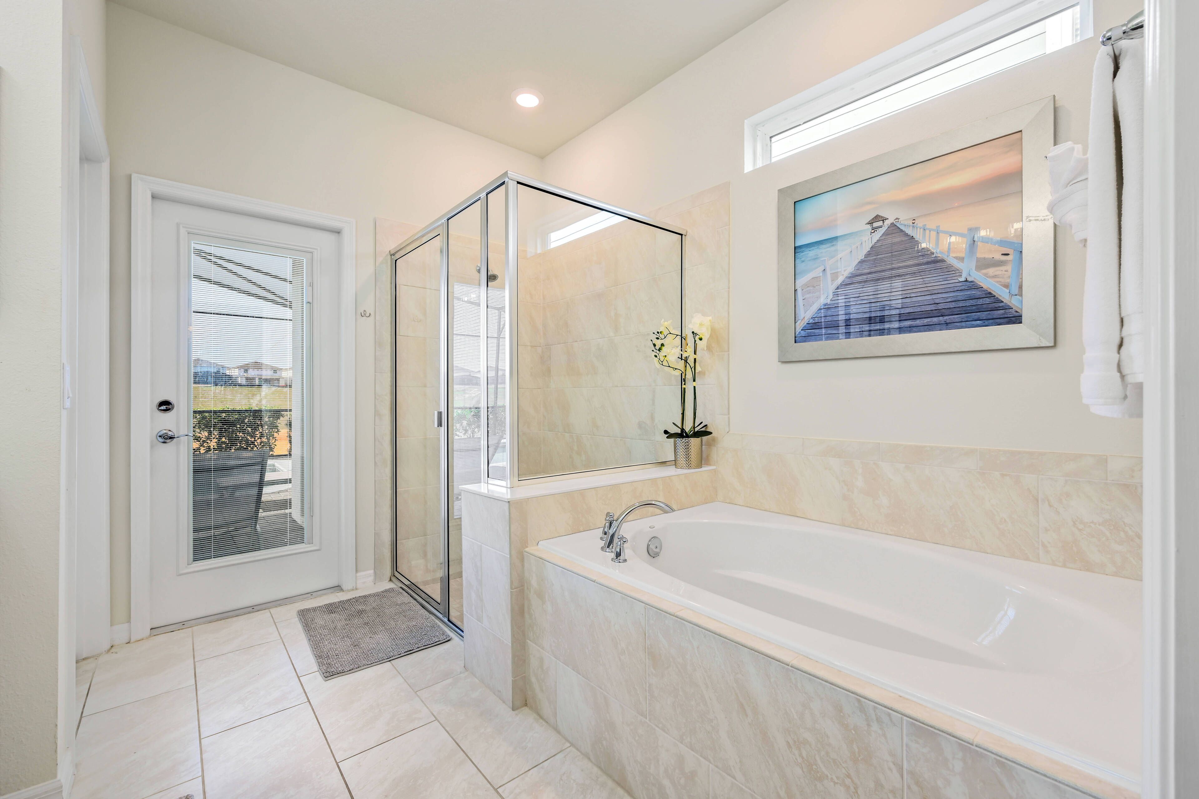 Un bagno moderno con cabina doccia in vetro, una vasca da bagno spaziosa e un quadro incorniciato che raffigura un molo.