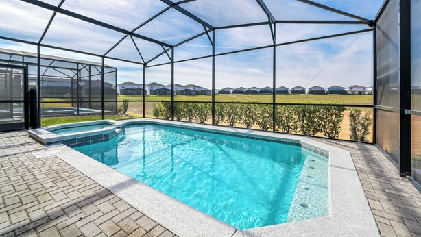 A swimming pool with a glass enclosure, surrounded by a brick patio. - Wi1196 - 7BR House With Pool Near Disney (Davenport)