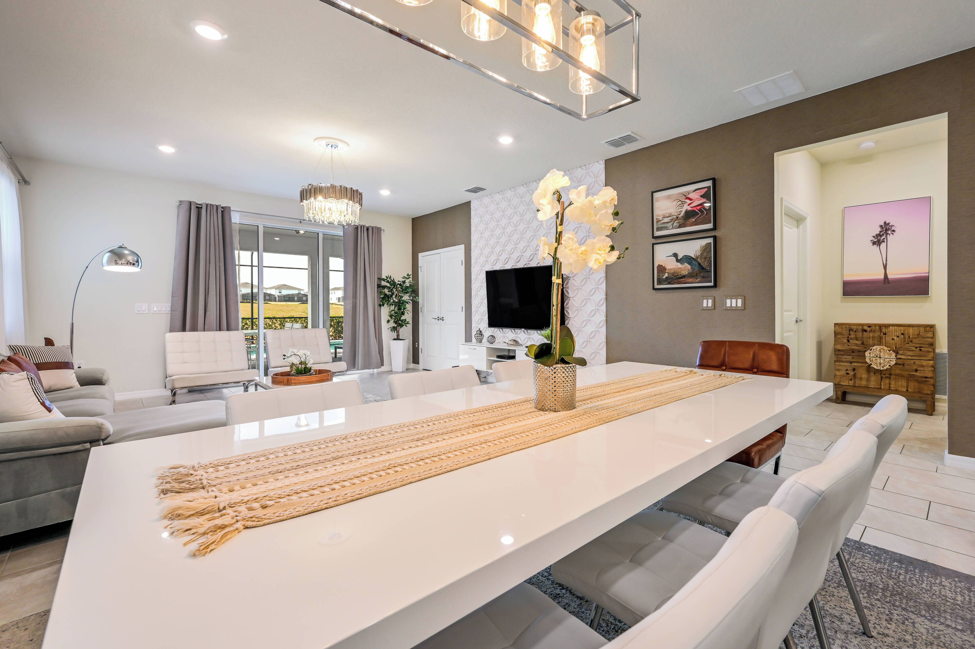 A modern living room with a large white dining table, a sofa, and a TV.