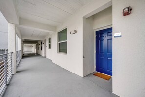 A corridor with a blue door marked 106, white walls, and a metal railing on the left. - Sl3111-106 - 2BR Apartment Near Disney Attractions (Kissimmee)