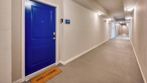 A hallway with a blue door, a welcome mat, and a number sign indicating room 204. - Vcr2-204 - 3BR Condo Near Disney and Universal (Orlando)