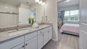 A modern bathroom with a granite countertop, a large mirror, and a walk-in shower. - Vcr4-410- 3BR Condo With Resort Access Near Disney (Orlando)