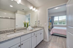 A modern bathroom with a granite countertop, a large mirror, and a walk-in shower. - Vcr4-410- 3BR Condo With Resort Access Near Disney (Orlando)