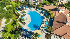 An aerial view of a resort with a central swimming pool, multiple lounge areas with umbrellas, and a variety of buildings with red-tiled roofs. - Vcr4-410- 3BR Condo With Resort Access Near Disney (Orlando)