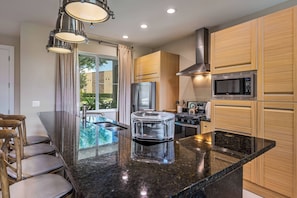 A modern kitchen with wooden cabinets, stainless steel appliances, and a granite countertop.