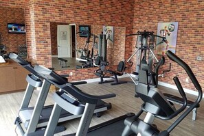 Uma academia com esteiras, aparelhos de musculação e um espelho.