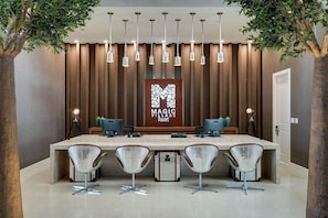 A modern reception area with a long counter, four chairs, and a sign reading "MAGIC VILLAGE Resort".