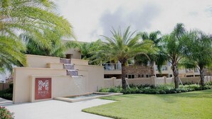 A hotel entrance with a palm tree-lined pathway, a water feature, and a sign reading "MAGIC". - Mvy7664 - 3BR House Near Disney With Hot Tub (Kissimmee)