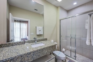 A bathroom with a granite countertop sink, a mirror, a toilet, and a glass-enclosed shower. - Mvy7664 - 3BR House Near Disney With Hot Tub (Kissimmee)