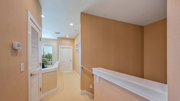A narrow hallway with beige walls, a white door at the end, and a white shelf on the right. - Mvy7664 - 3BR House Near Disney With Hot Tub (Kissimmee)