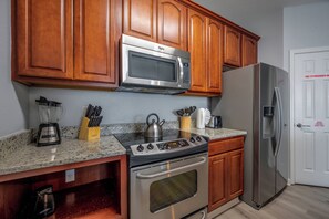 A kitchen with wooden cabinets, a stainless steel microwave, a gas stove, a refrigerator, and a blender. - Is4-405 - 3BR Condo With Nature View Near Disney (Orlando)