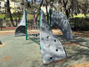 Un parque infantil con estructuras para escalar y una zona delimitada por una valla.