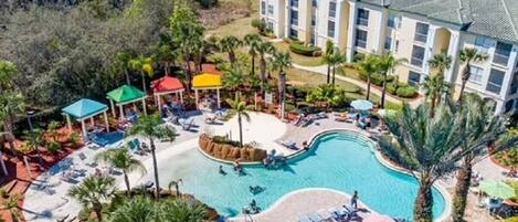 A resort with a swimming pool, palm trees, and a building with multiple floors.