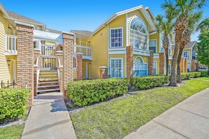 A multi-story residential building with a brick facade, large windows, and a well-maintained lawn. - Sw40 - 3BR Apartment Near Disney With Resort Pool (Kissimmee)