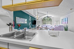 Eine moderne Küche mit weißer Arbeitsplatte, Spüle aus Edelstahl und einer Glasschüssel.