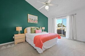 Ein Schlafzimmer mit einem Bett, Nachttischen, einem Deckenventilator und einem Fenster mit Vorhängen.