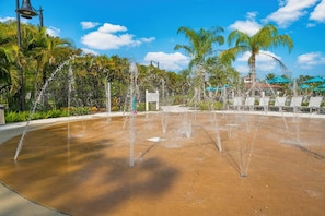 A water fountain with multiple jets, surrounded by palm trees and a clear blue sky. - Vcr1-104 - 3BR Condo at Vista Cay Resort (Orlando)