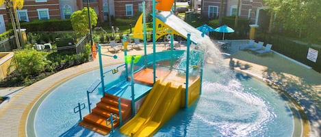 A water park with a water slide, pool, and surrounding buildings.