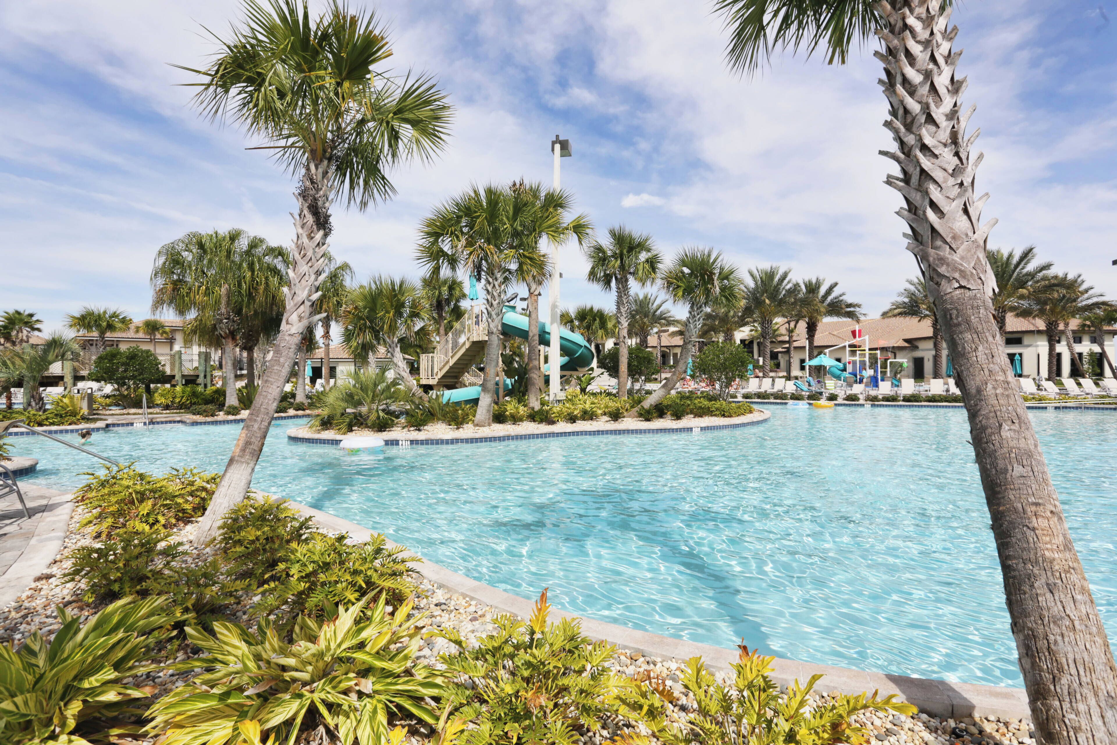 A swimming pool surrounded by palm trees and a water slide.