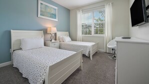 A bedroom with two beds, a bedside table with lamps, a TV mounted on the wall, and a window with curtains. - Cg1569 - 5BR House With Pool Near Disney Parks (Davenport)