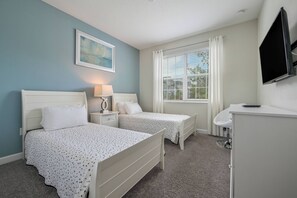 A bedroom with two beds, a bedside table with lamps, a TV mounted on the wall, and a window with curtains. - Cg1569 - 5BR House With Pool Near Disney Parks (Davenport)