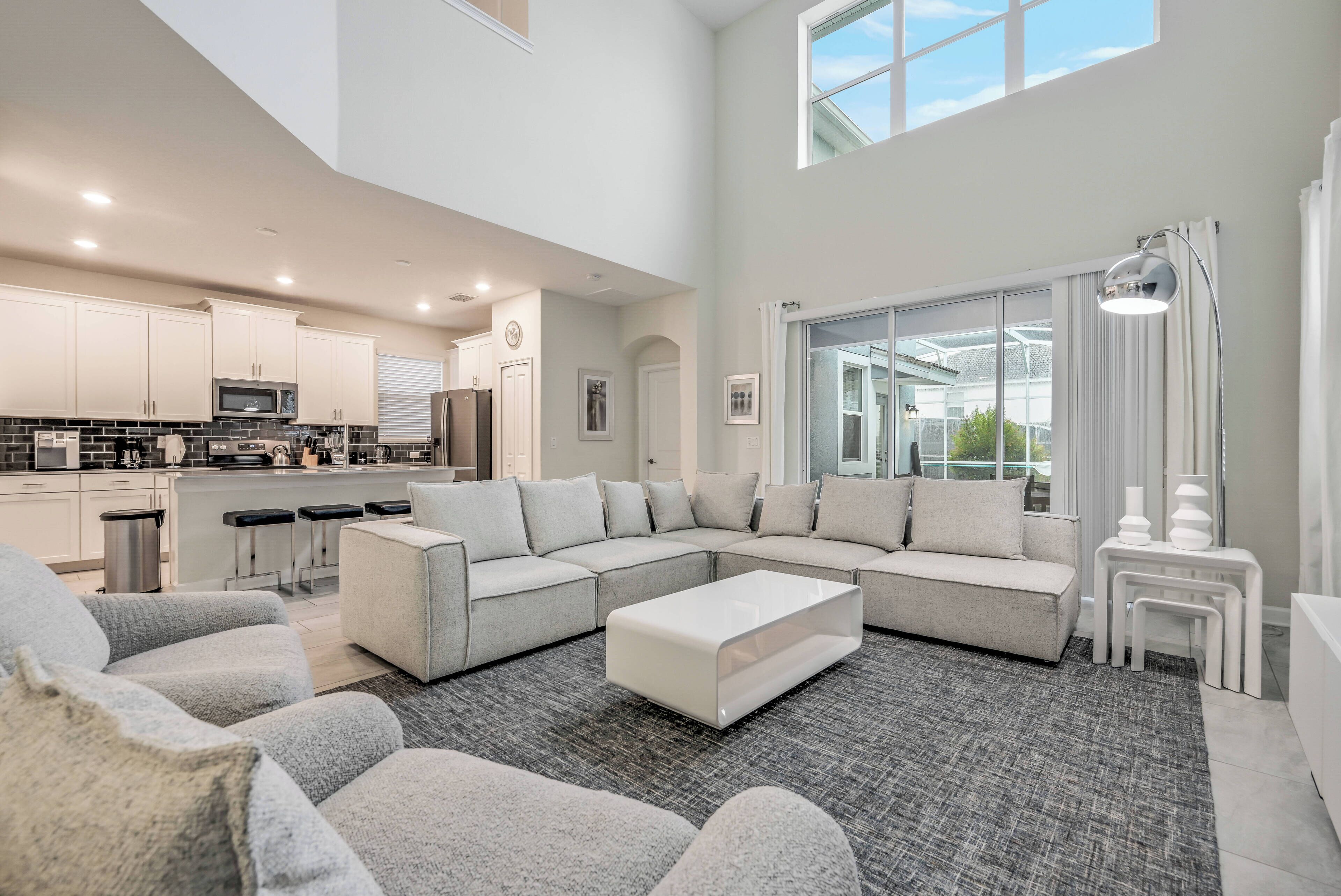 A spacious living area with a large sectional sofa, a coffee table, and a kitchen in the background.