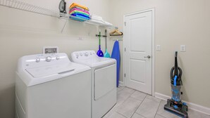 A laundry area with two washing machines, a stacked drying rack, and a vacuum cleaner. - Cg1569 - 5BR House With Pool Near Disney Parks (Davenport)