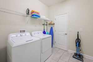 A laundry area with two washing machines, a stacked drying rack, and a vacuum cleaner. - Cg1569 - 5BR House With Pool Near Disney Parks (Davenport)